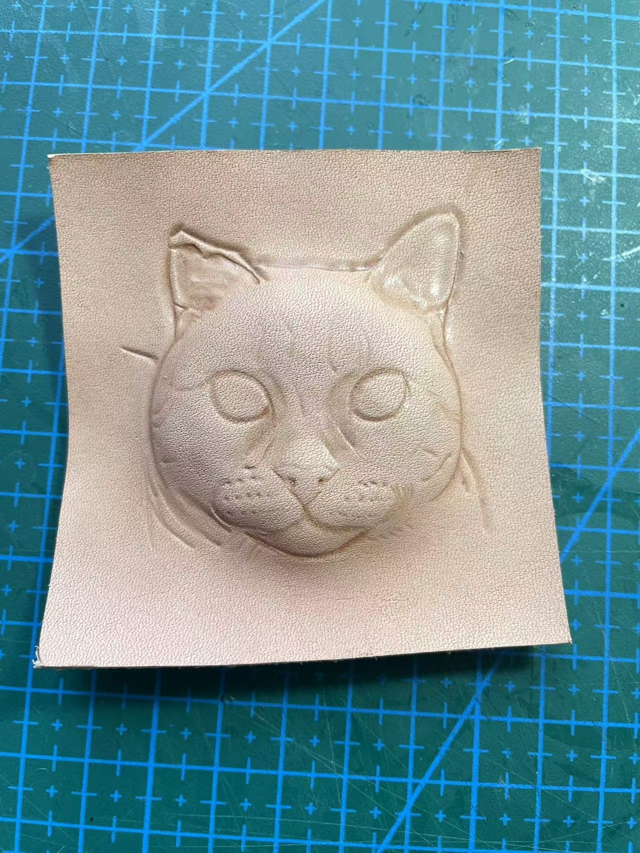 Early hand-carving stage of a custom cat portrait on vegetable-tanned leather