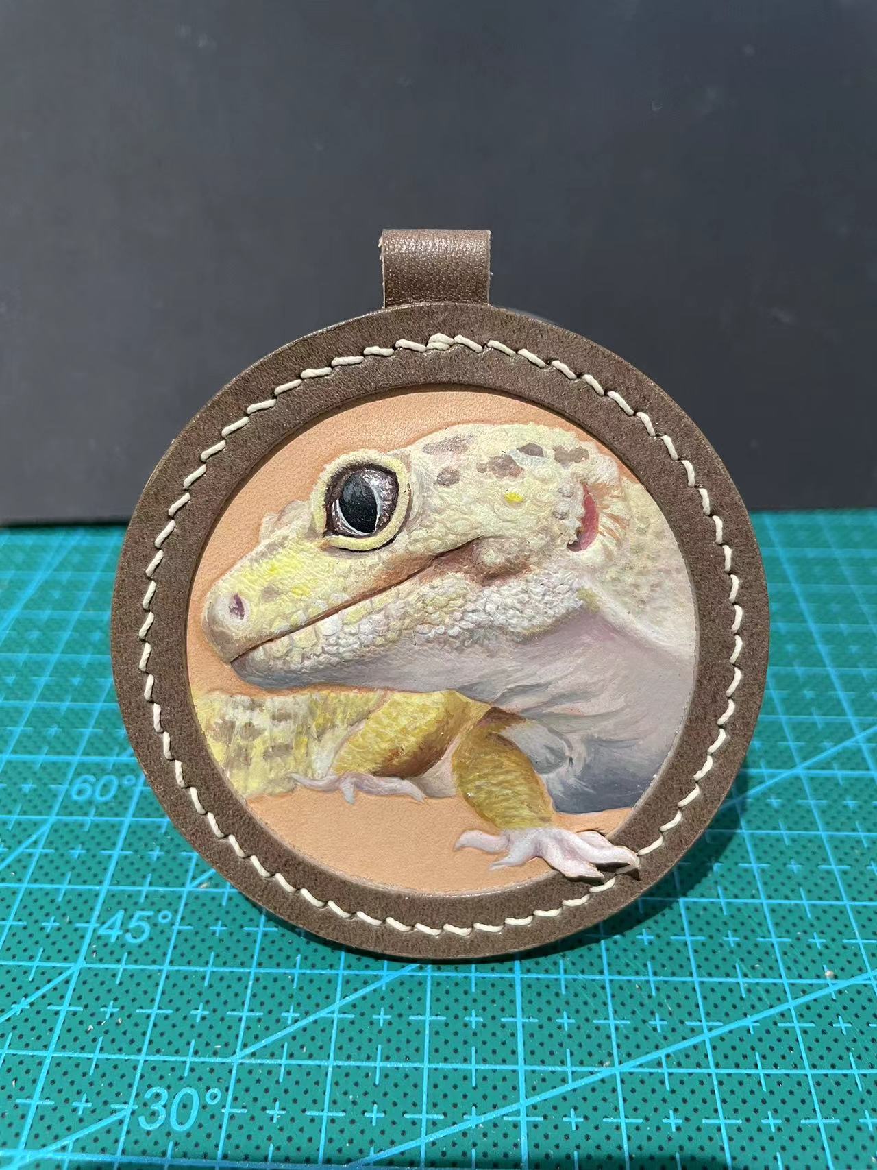 Close-up of carved gecko portrait in round vegetable-tanned leather frame